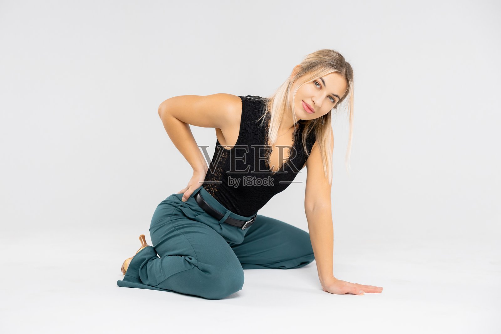 舞者跪姿摆拍，手扶后腰，背景为白色照片摄影图片