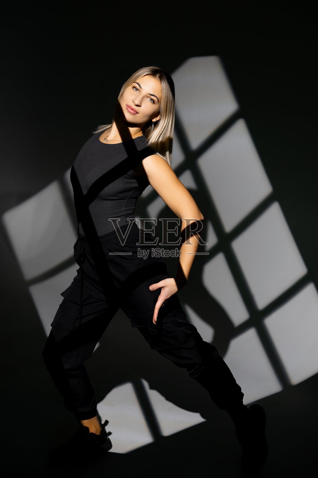 年轻舞者在窗户形状的阴影背景下表演照片摄影图片