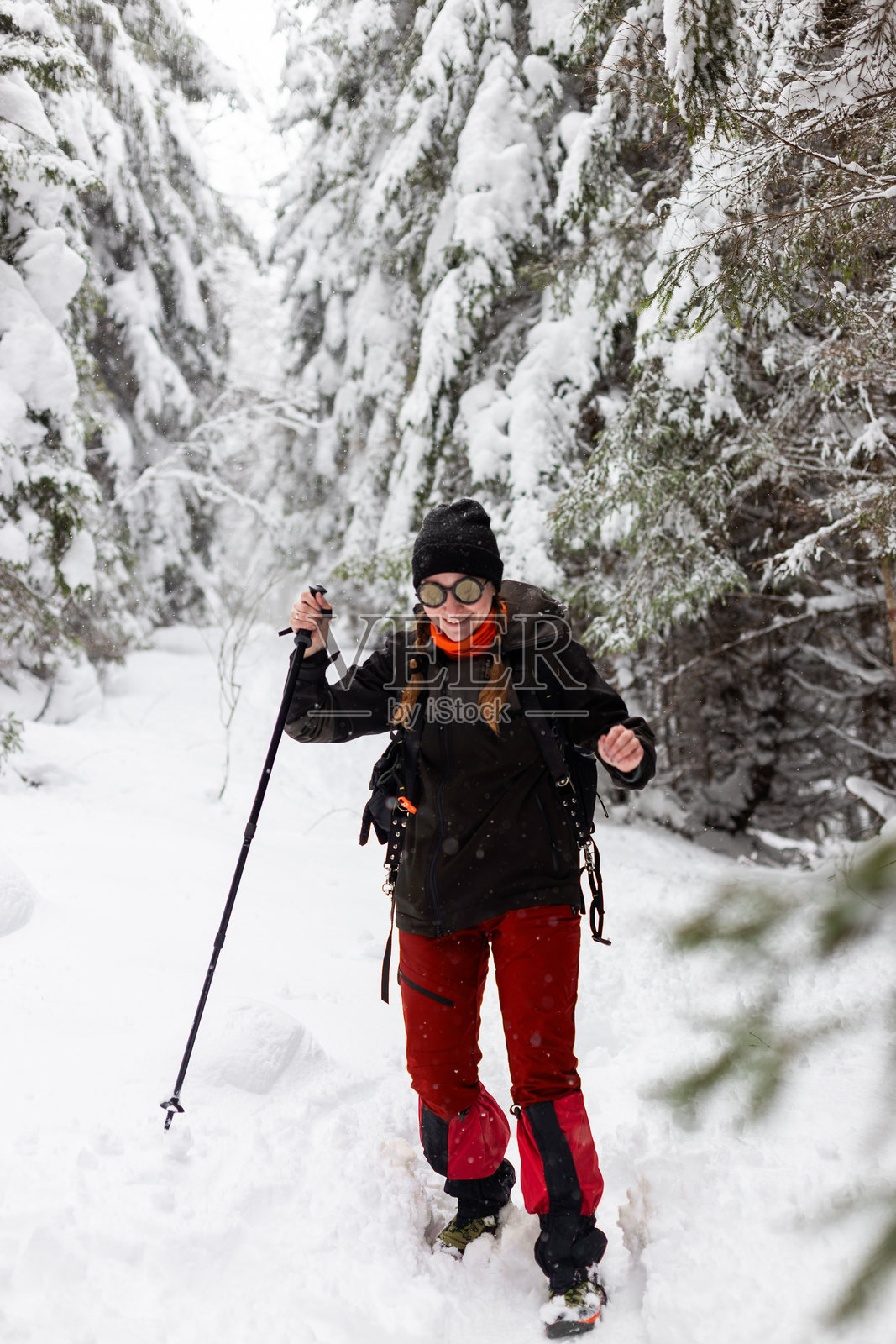 一位快乐的探险家在午后阳光下，穿越白雪覆盖的森林，进行冬季徒步探险照片摄影图片