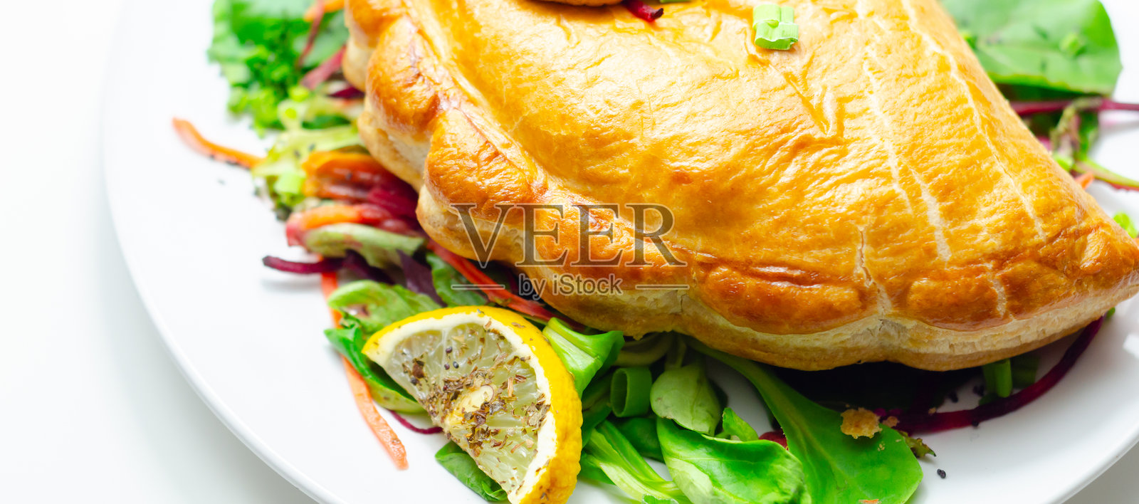 盘子里放着食物，上面有一个肉馅饺子和一片柠檬角照片摄影图片