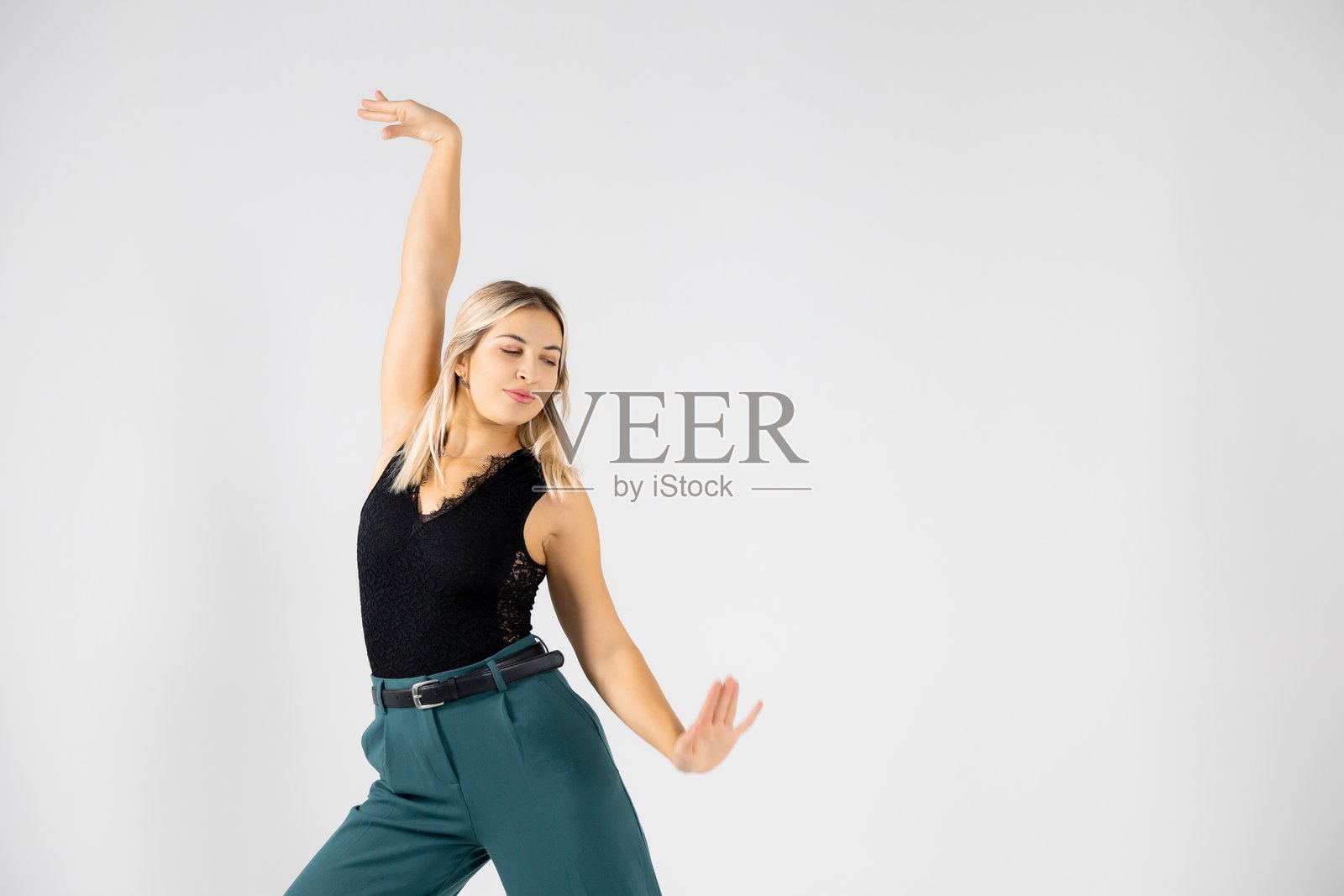 年轻的金发舞者双手合十、双腿分开，在白色背景上摆出姿势照片摄影图片