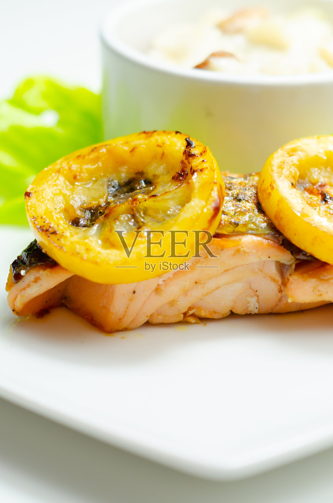 一盘食物，上面有一块三文鱼和几片黄色的柠檬照片摄影图片