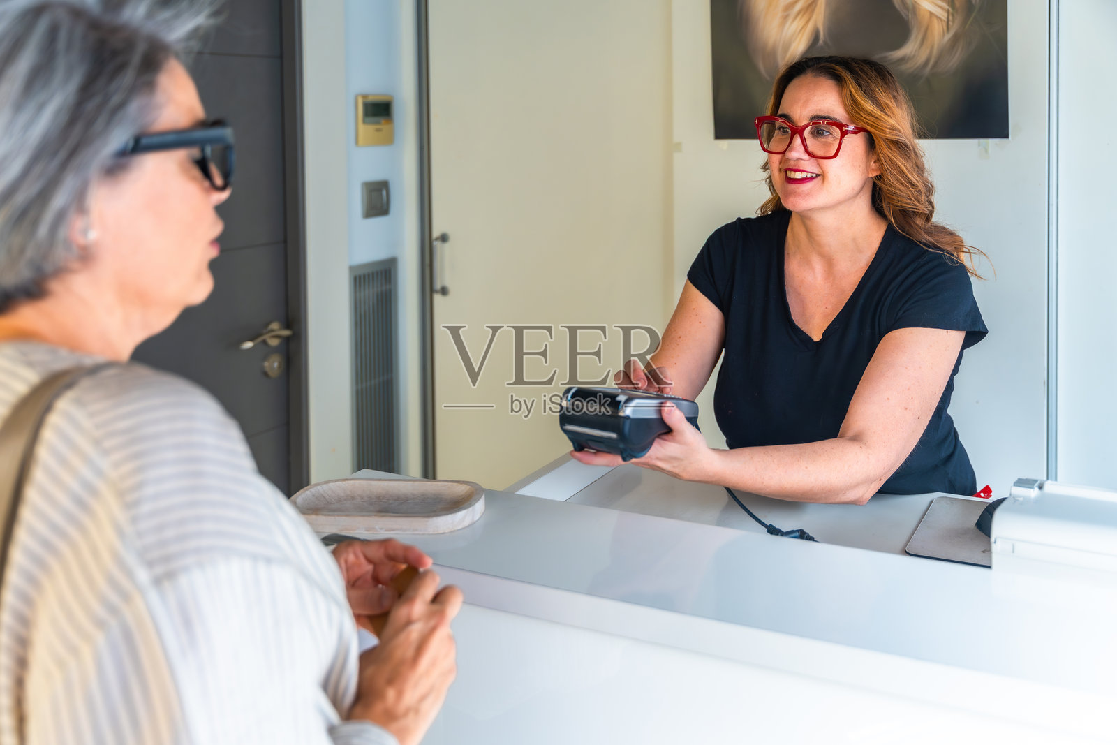 女性顾客为美发沙龙服务付款照片摄影图片