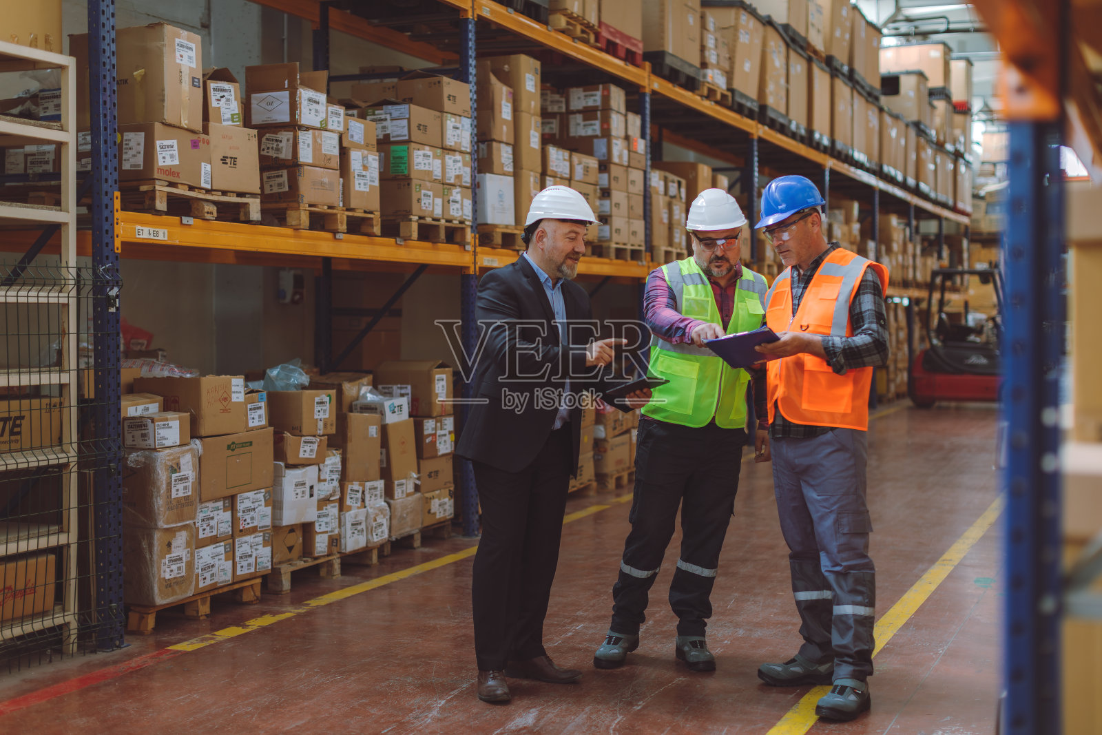 资深仓库经理和工人正在现代物流设施中使用数字技术照片摄影图片