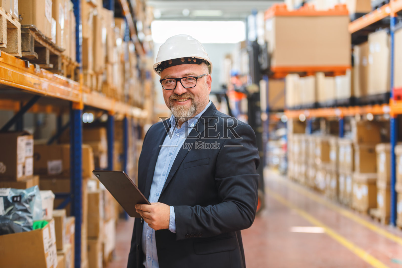 仓库高级经理在大型配送中心进行库存检查时，使用平板电脑拍摄肖像照片摄影图片