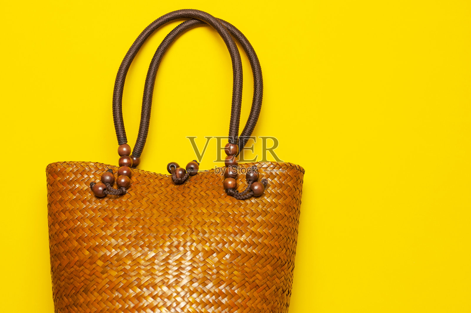 黄色背景下的沙滩柳条草编或藤编女士环保包。俯视平面图，留有复制空间。旅行概念。夏日明亮背景。沙滩配饰、女士夏日包、手提包、时尚照片摄影图片