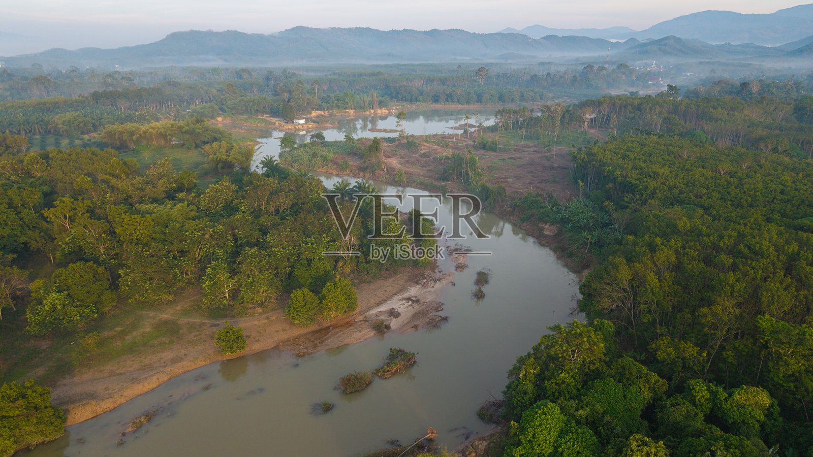 俯视热带绿色森林，河流如运河般穿过，晨曦初露照片摄影图片