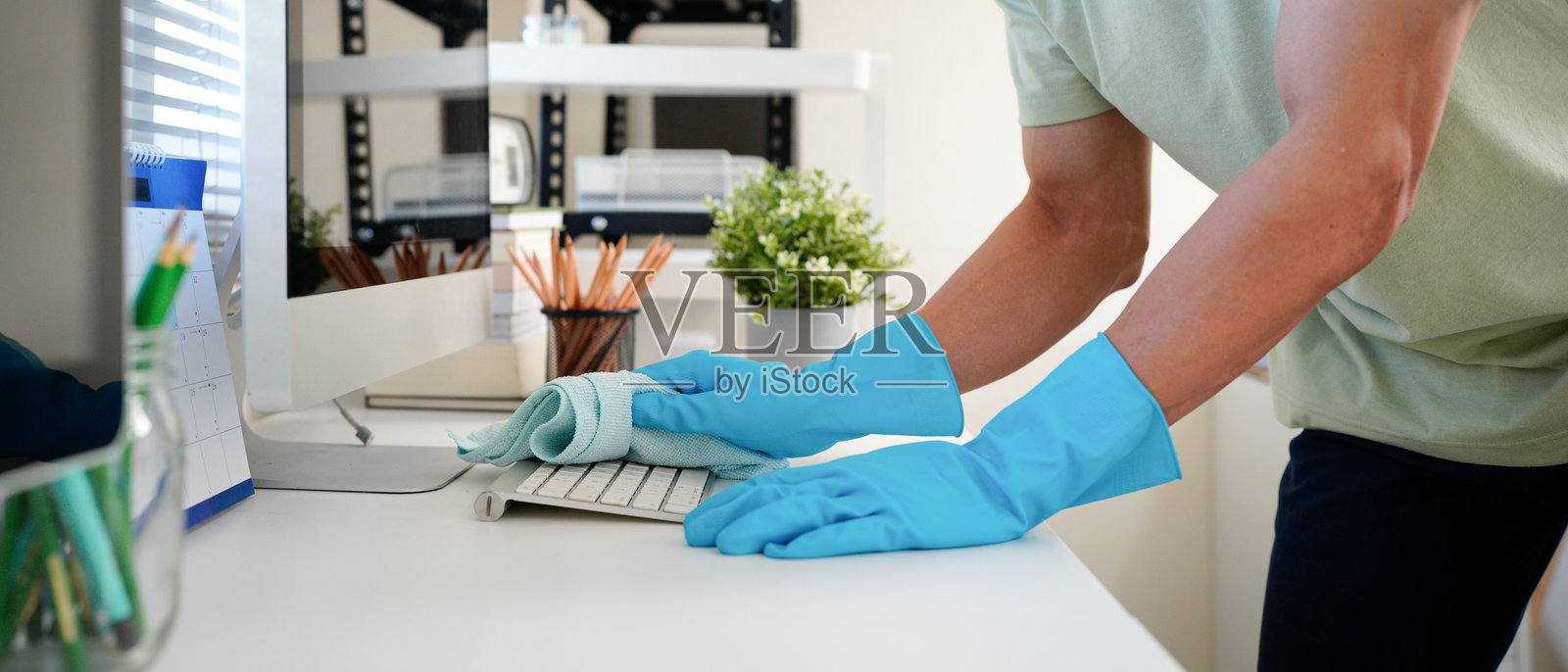 清洁人员在公司办公室里用抹布擦拭电脑键盘。清洁员工。组织机构的清洁理念。照片摄影图片