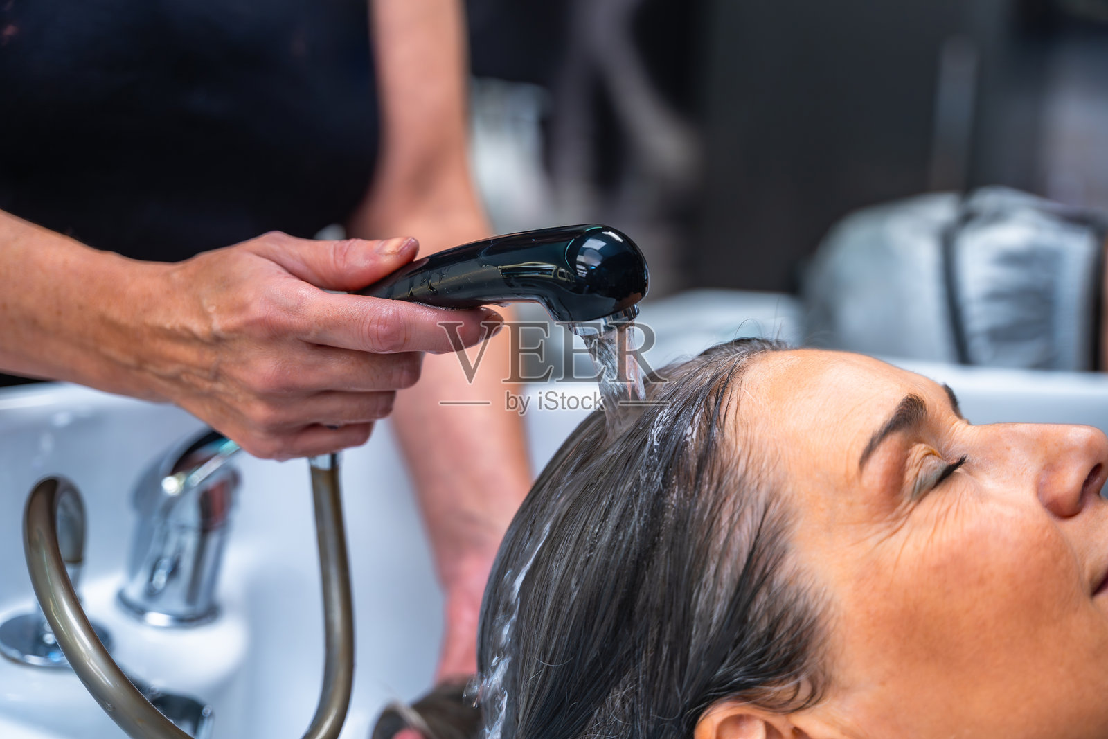 发型师在沙龙洗头盆为女士洗头，营造放松氛围照片摄影图片