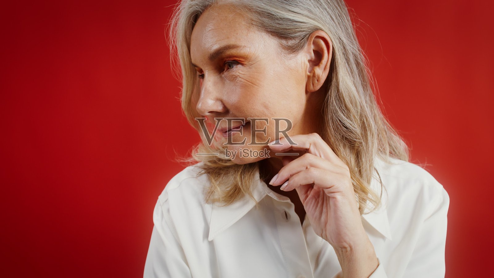 一位妆容鲜艳的老年女性，在单色背景前摆姿势。照片摄影图片