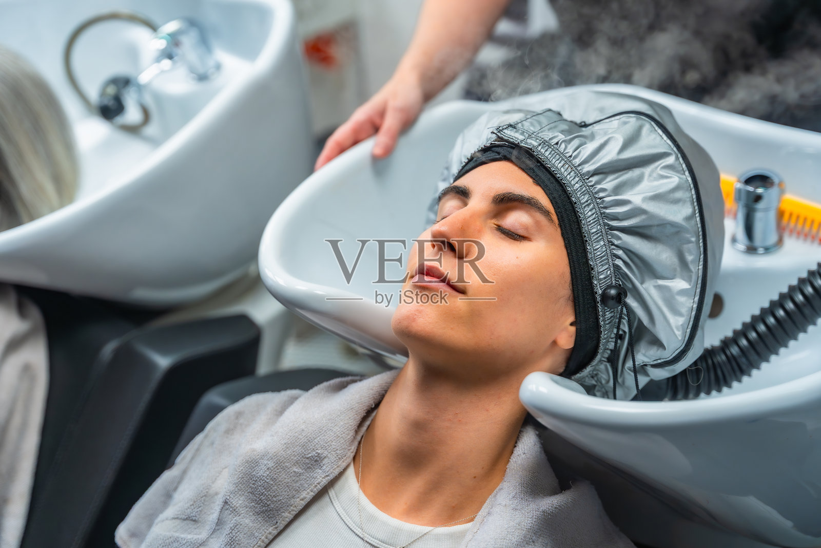 沙龙里有人正在接受蒸汽护发护理照片摄影图片