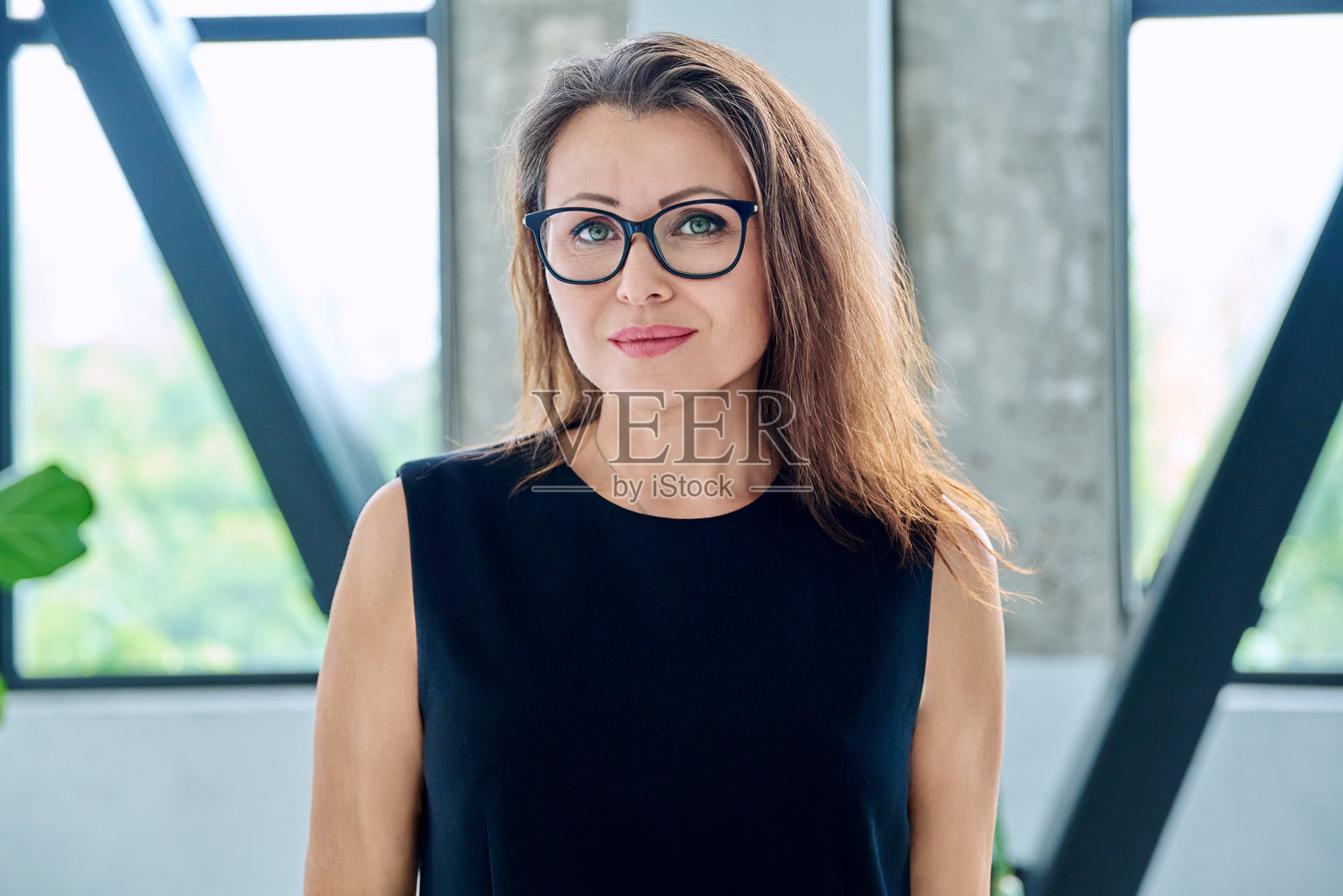 戴眼镜、表情严肃的中年女商人的头像肖像照片摄影图片