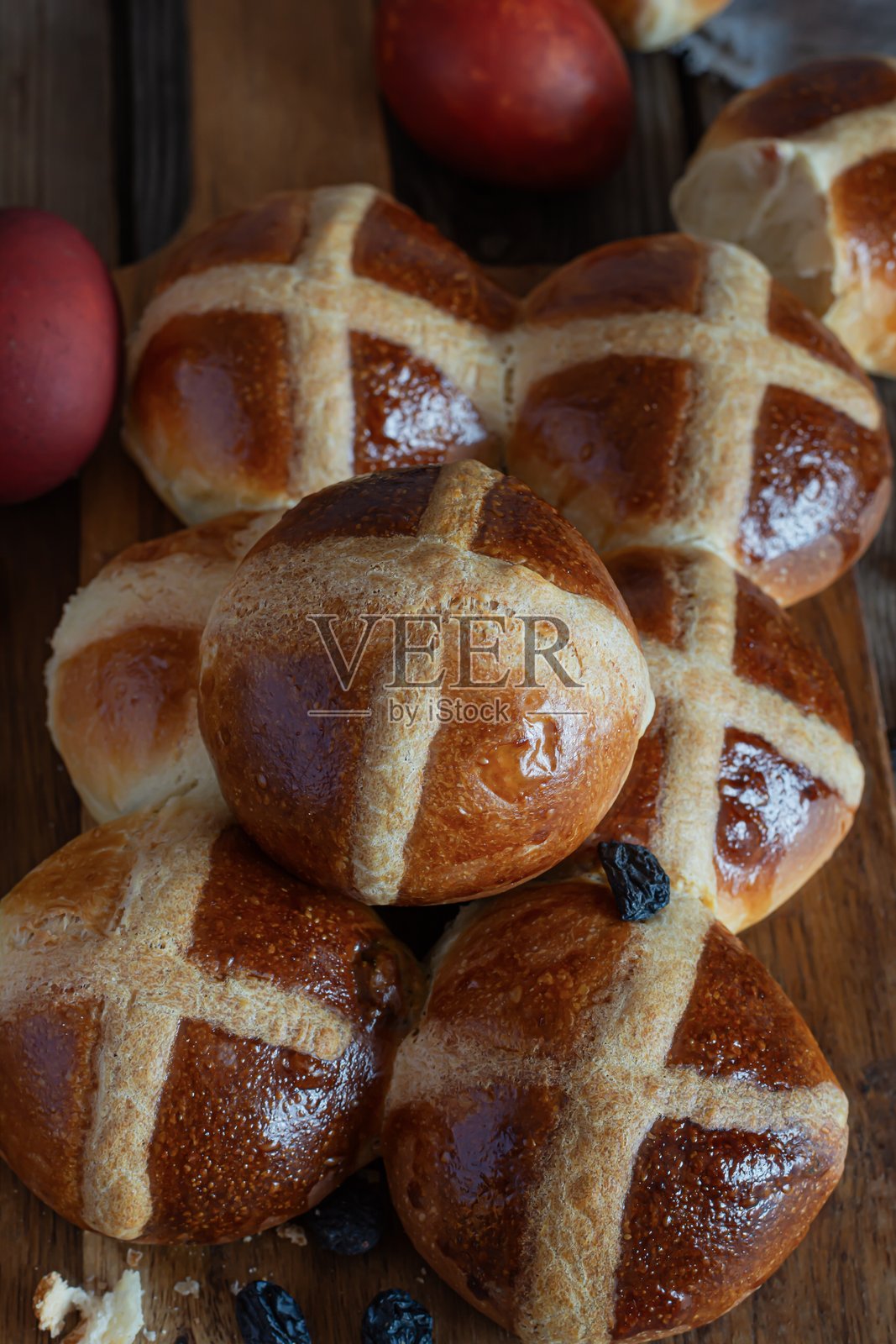 复活节期间售卖的传统英式（欧式）点心，带有葡萄干的热十字面包，放在木板上。美味的甜点心。照片摄影图片