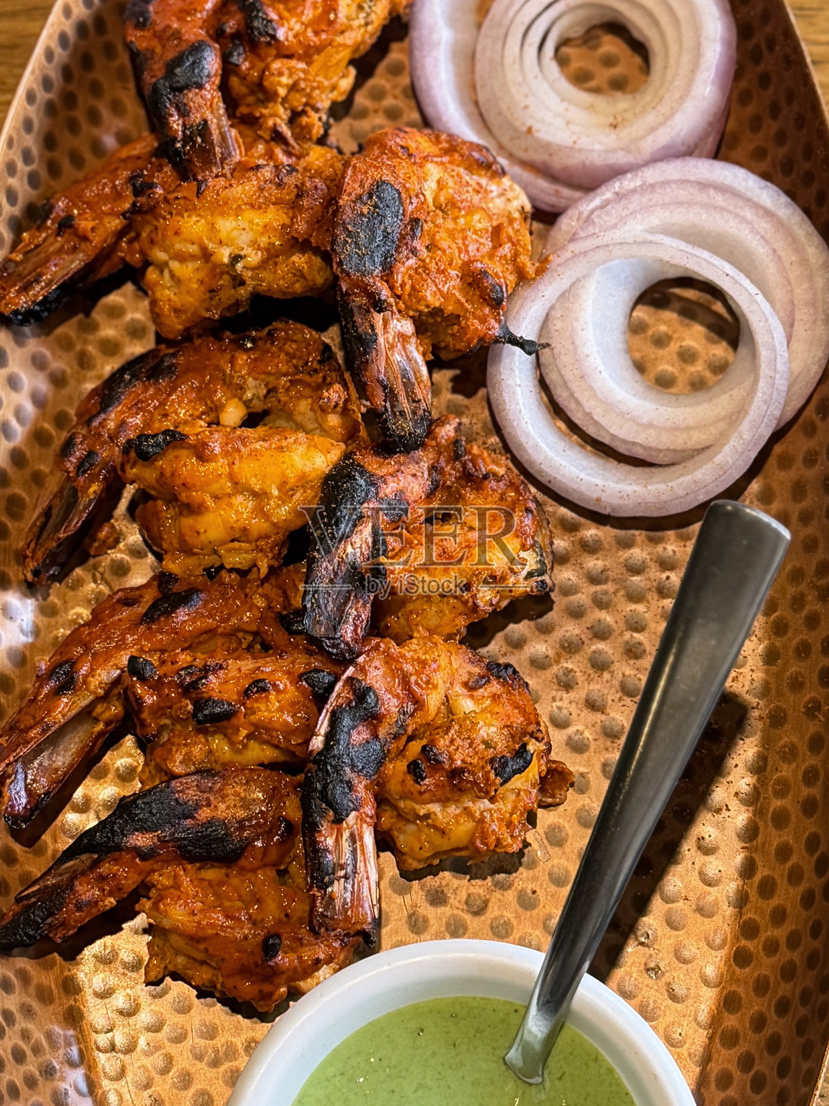 坦都里大虾玛莎拉，餐厅风格的印度菜，配以洋葱、薄荷、香菜和绿色蘸酱照片摄影图片