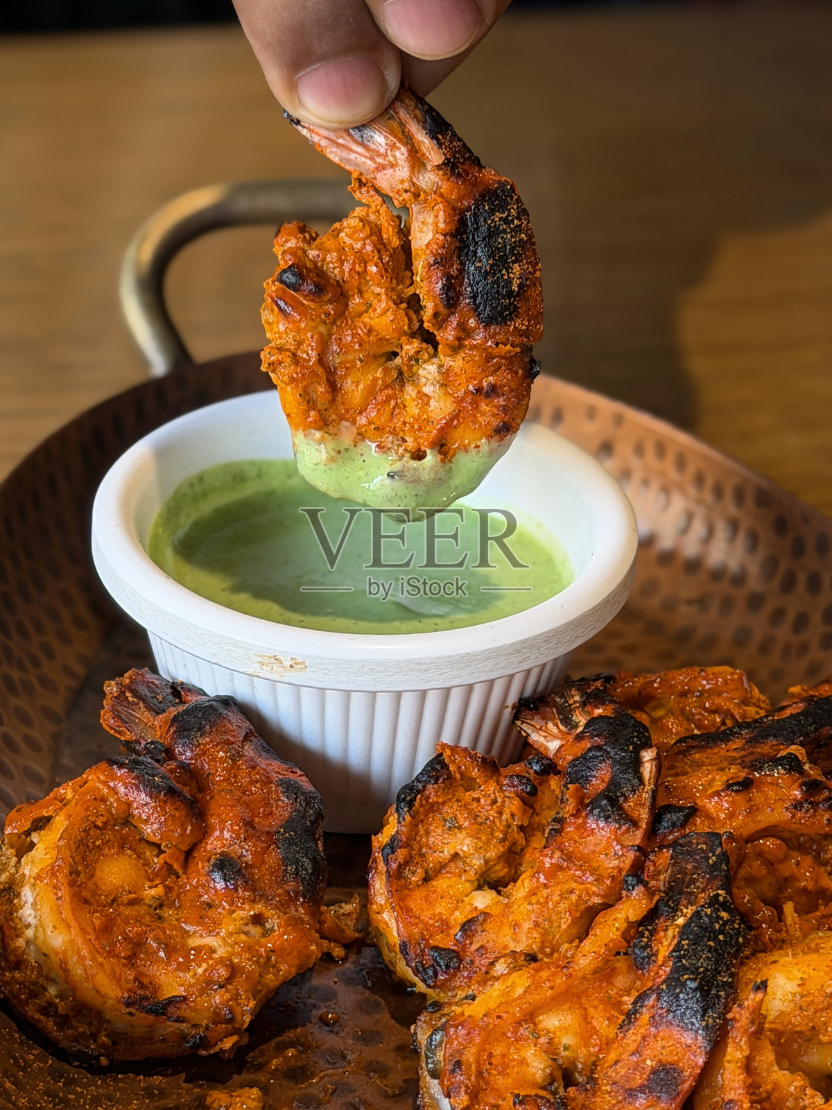 手蘸印度香料烤虾，配以新鲜洋葱、薄荷、香菜和绿色蘸酱，烟熏烤海鲜配菜照片摄影图片