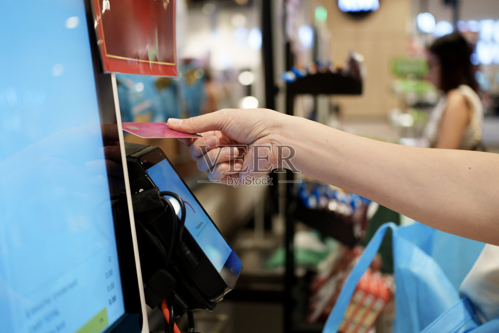 顾客在超市自助结账柜台进行非接触式银行卡支付照片摄影图片