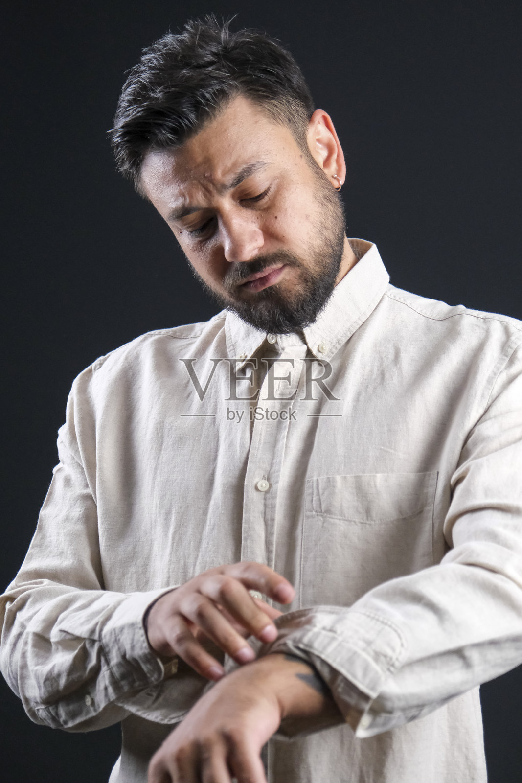 魅力十足的中年深色头发男子，身着休闲服饰，在戏剧化灯光下，于深黑色影棚背景前摆姿势照片摄影图片