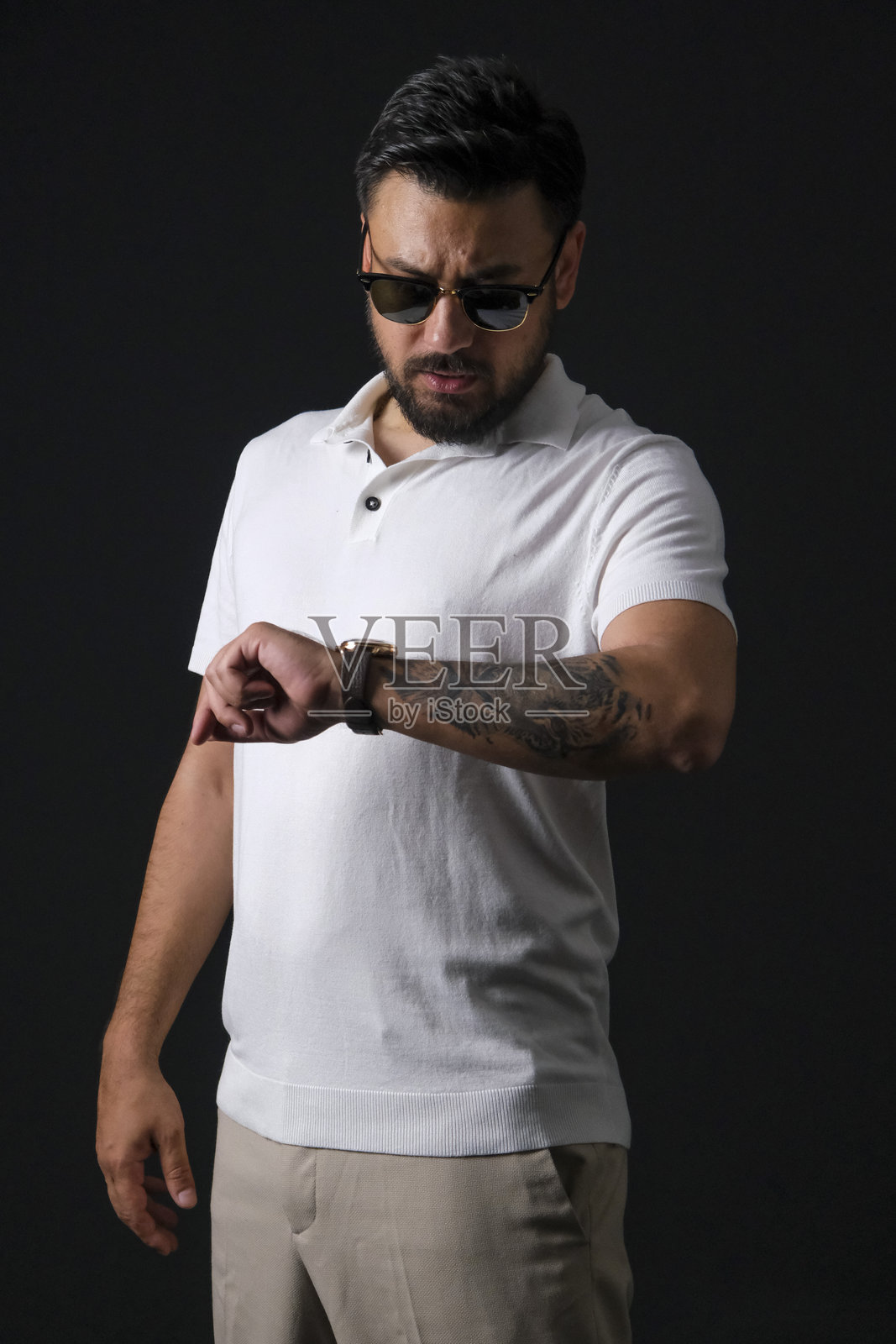 身着休闲装、富有魅力的中年棕发男子在戏剧性灯光下，于深黑色影棚背景前摆姿势照片摄影图片