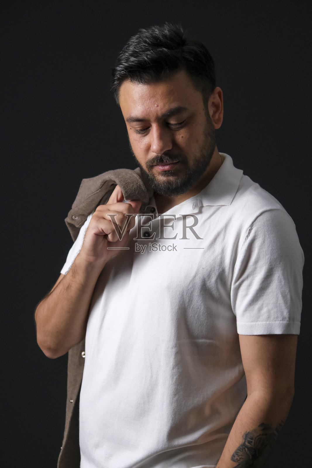 魅力十足的中年棕发男子，身着休闲装，在黑色暗调影棚背景前摆姿势，灯光戏剧化照片摄影图片