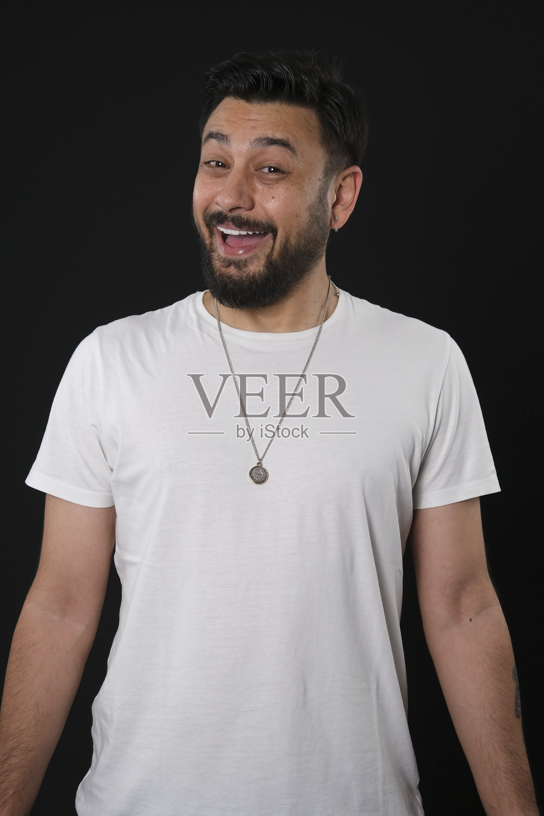 一位魅力十足的中年棕发男子，身着休闲装，在黑暗的黑色工作室背景前摆姿势，灯光戏剧化照片摄影图片