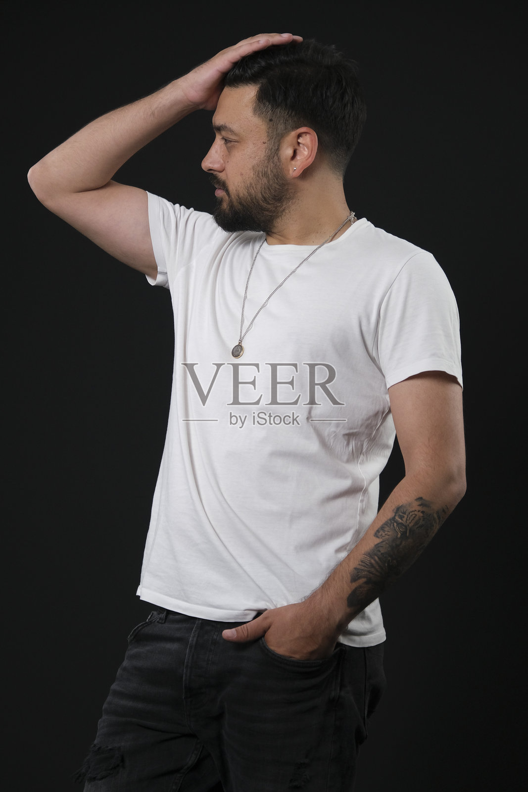 一位富有魅力的中年棕发男子，身着休闲装，在黑色影棚背景前摆出造型，灯光戏剧化照片摄影图片