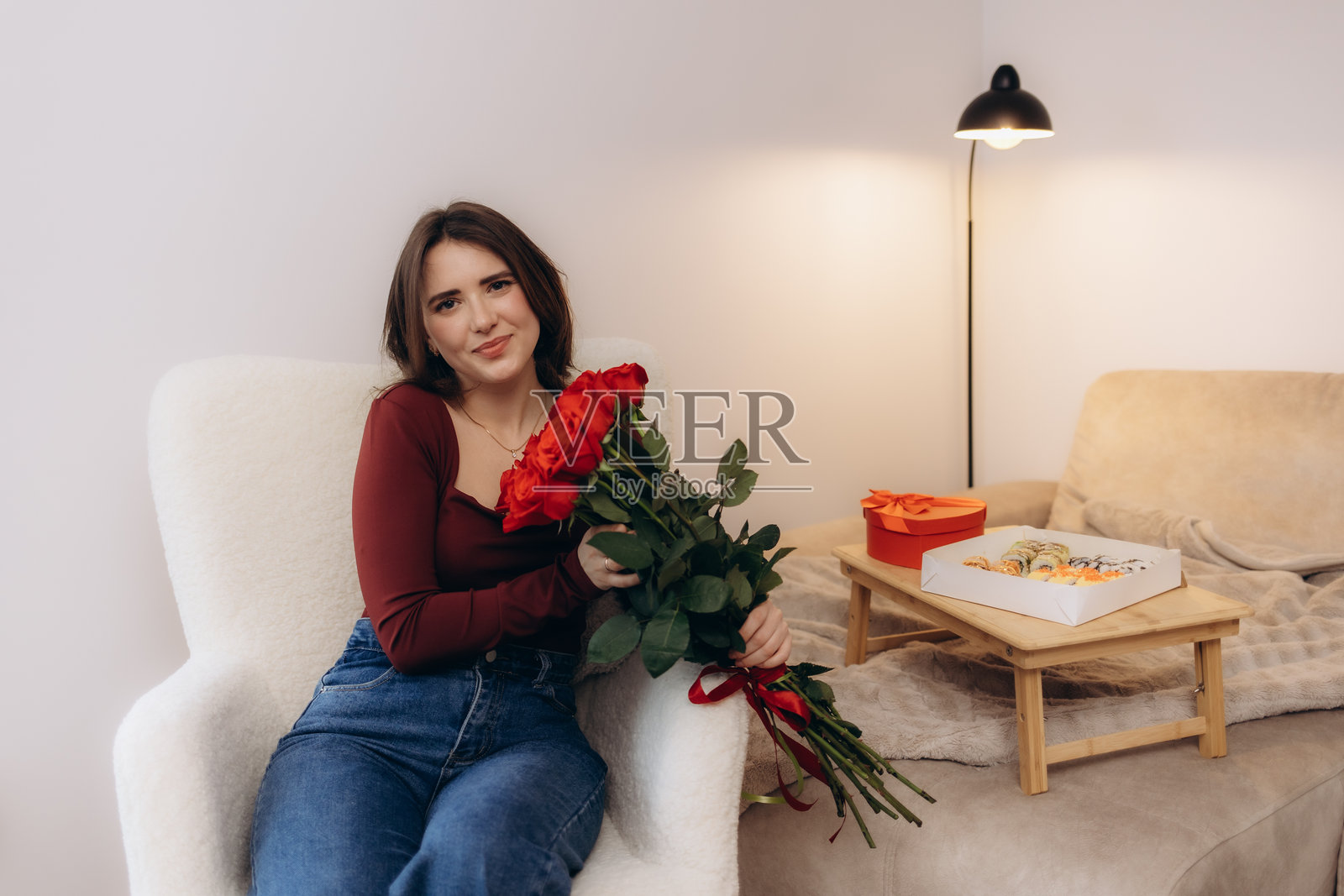 一位女士在舒适的客厅里手捧一束红玫瑰照片摄影图片