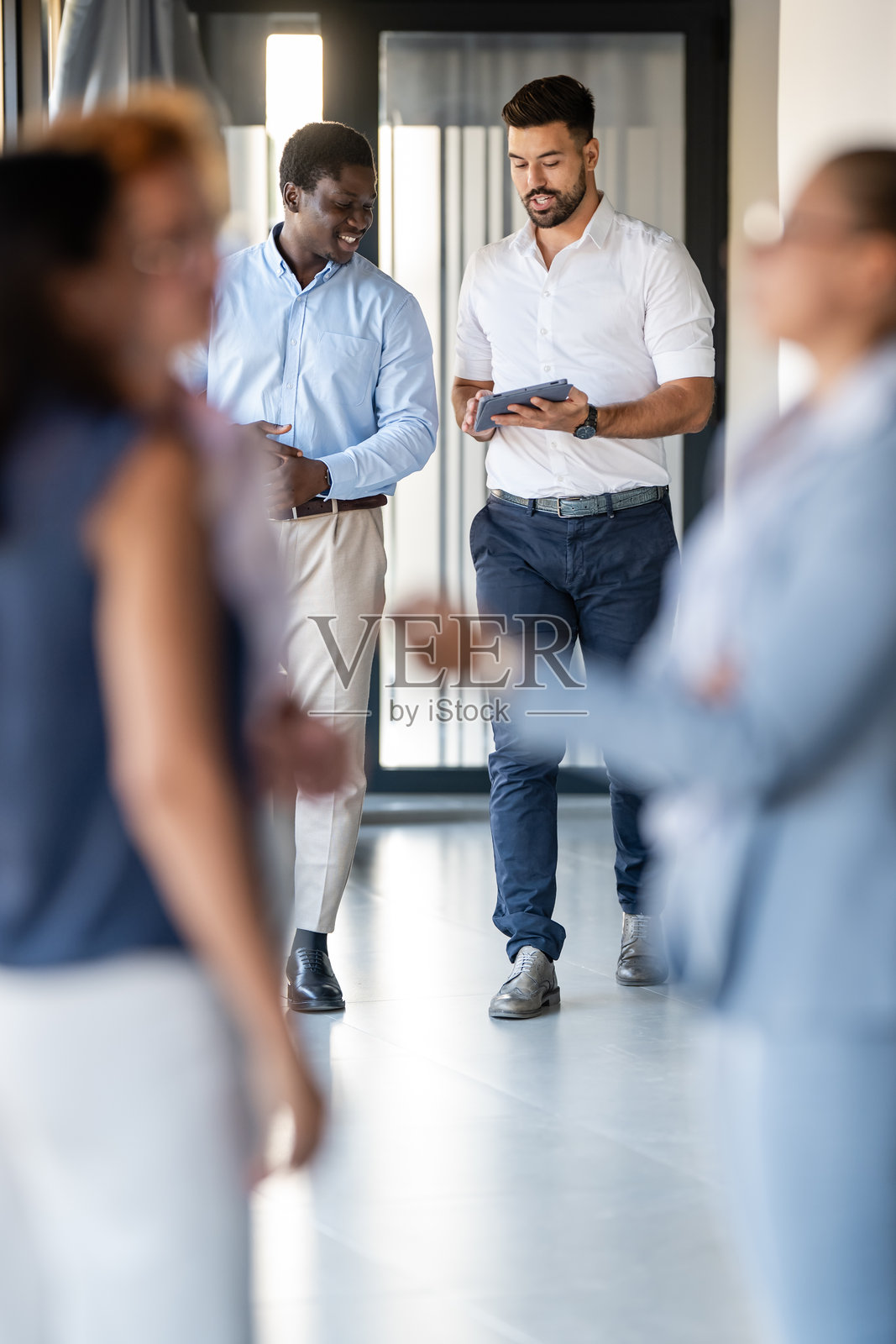 成功的多元化商务同事在现代办公室走廊里一起行走照片摄影图片