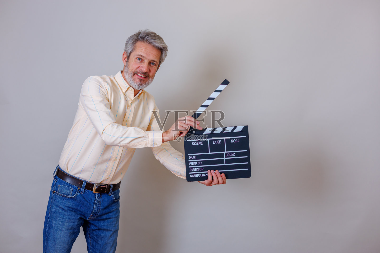 一位成熟的成年男子微笑着，手持电影拍板，在片场准备拍摄照片摄影图片