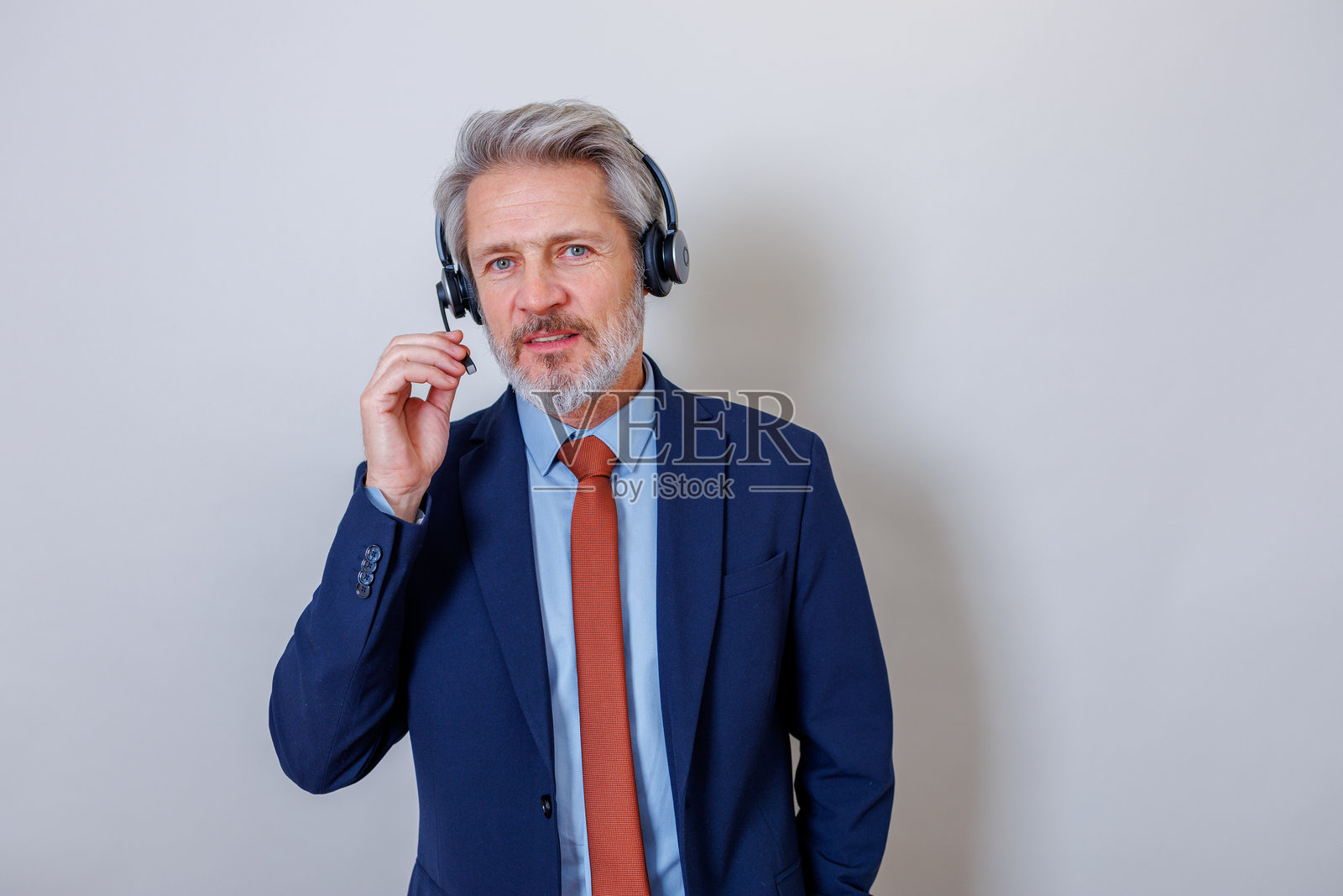 穿着西装、戴着耳机的成熟成年男性，提供专业的客户服务与支持照片摄影图片