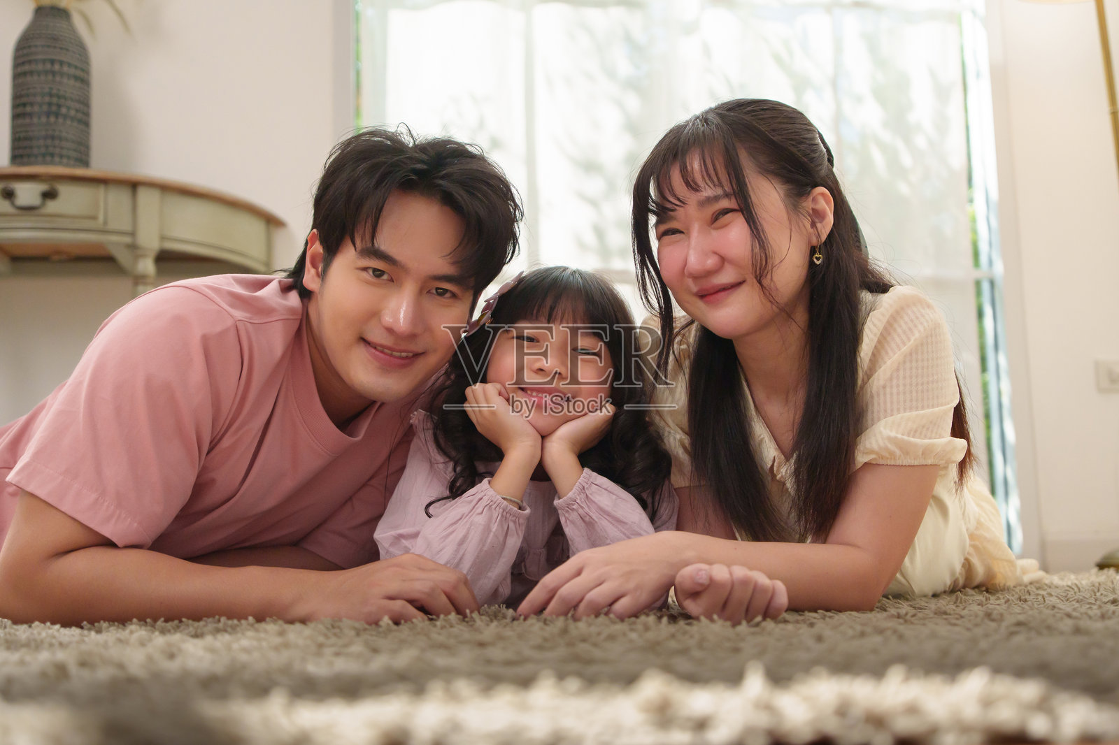 快乐的亚裔家庭肖像，在家里躺在地毯上照片摄影图片
