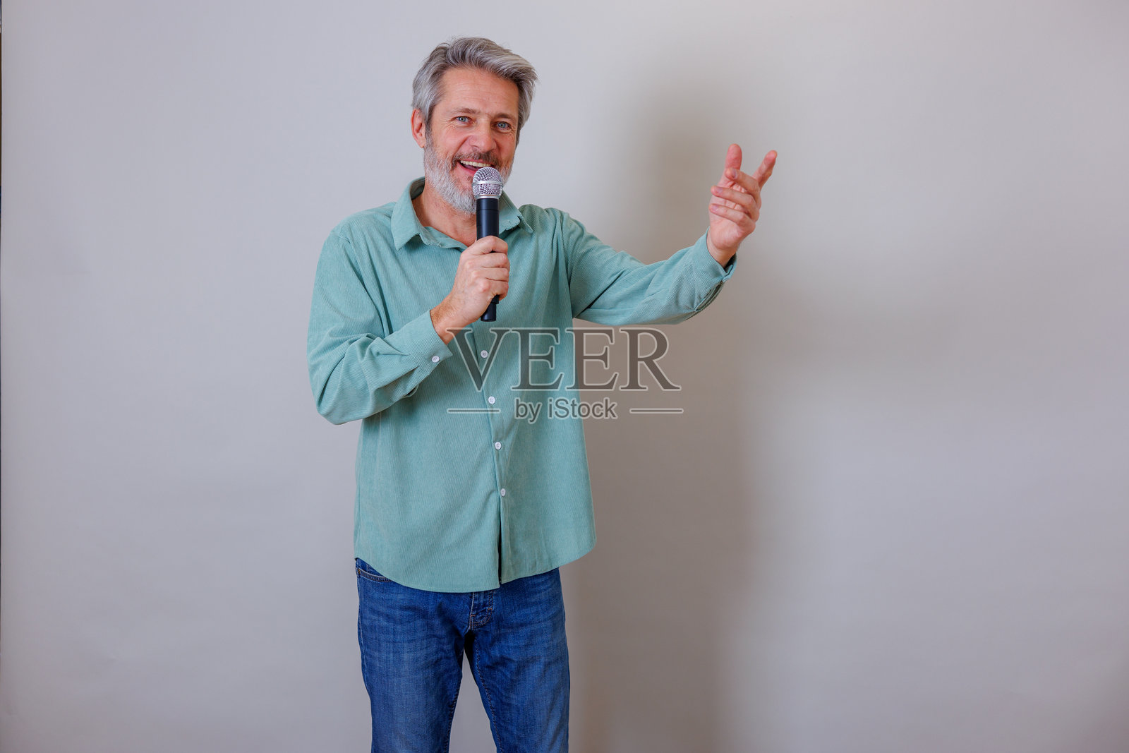 一位成熟的男士正在对着麦克风唱歌并做出手势，在卡拉OK或公开演讲活动中表演照片摄影图片