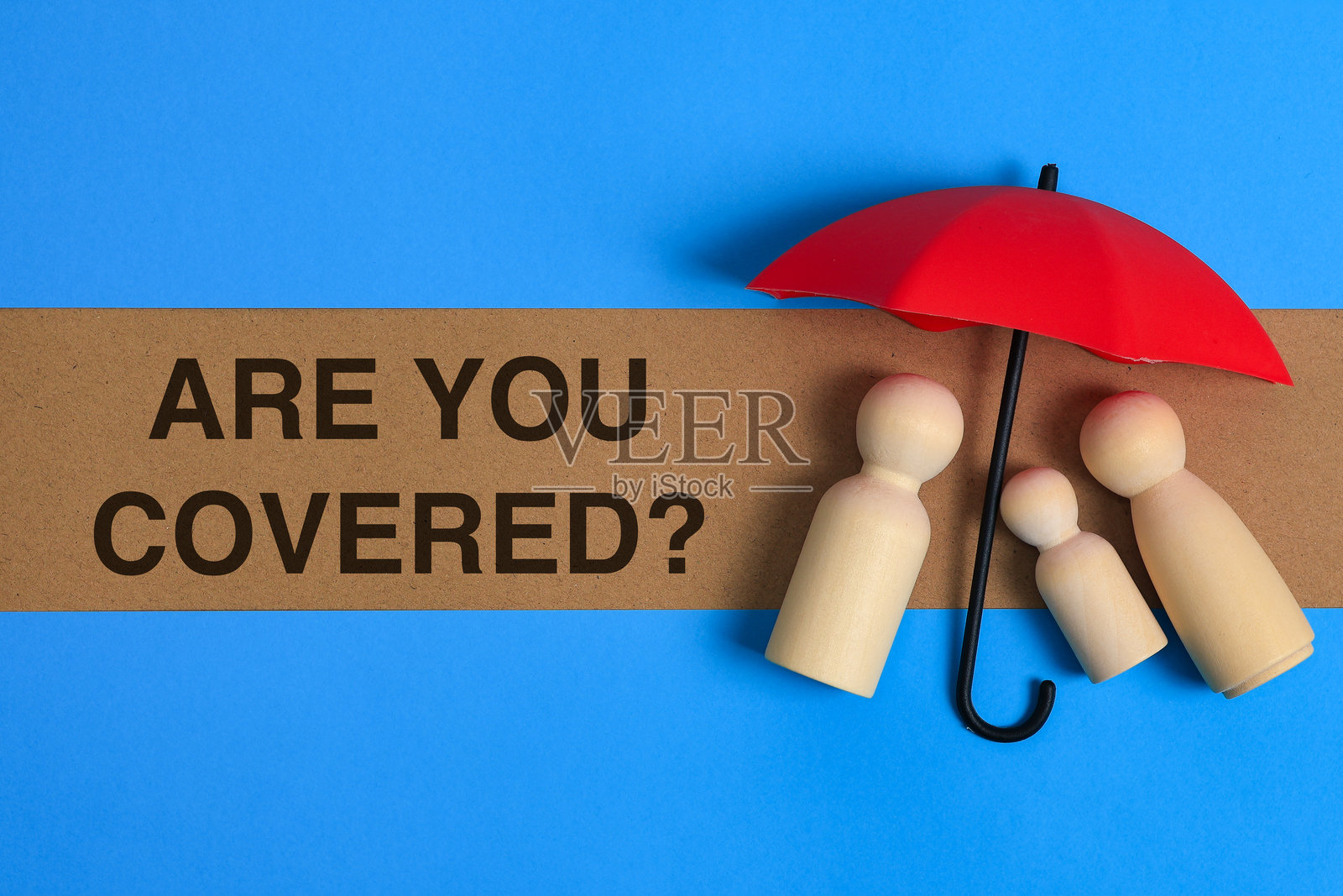 红色玩具雨伞保护木制家庭别针人偶，保险覆盖概念照片摄影图片