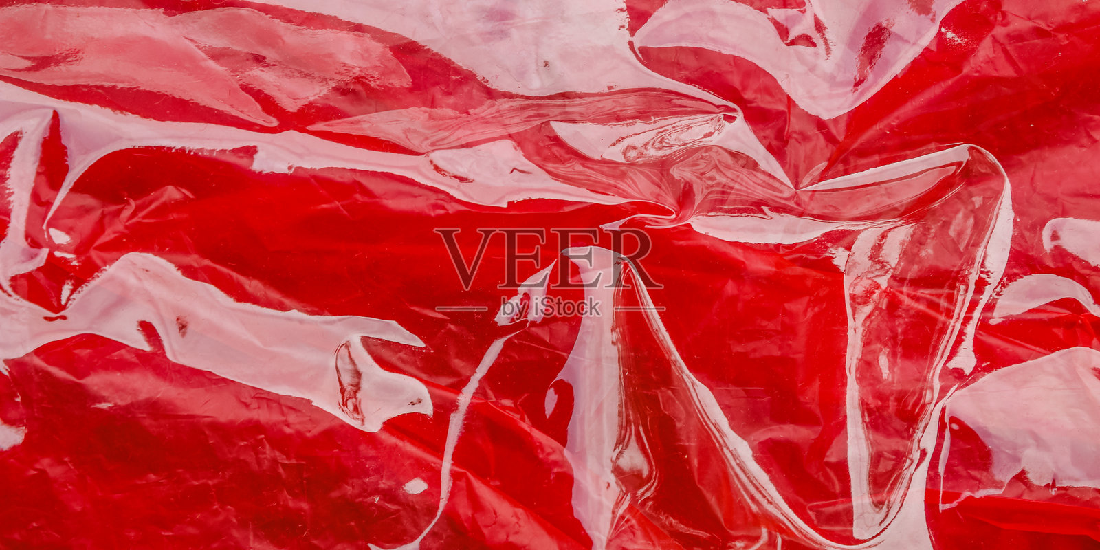 红色塑料的纹理起皱，并且在光线反射下闪闪发光。照片摄影图片