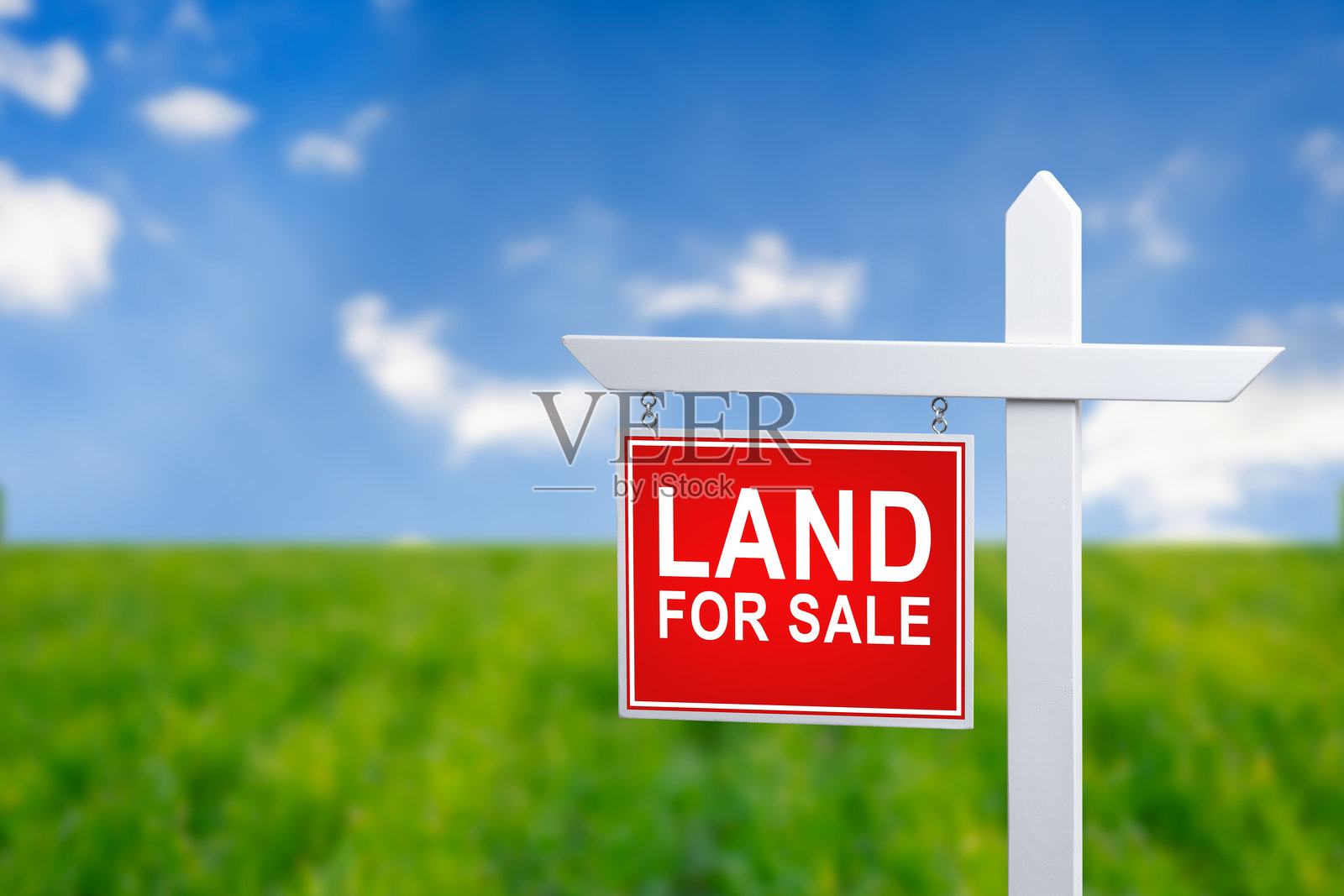 出售土地的标志，背景是美丽的绿色田野和蓝天。照片摄影图片