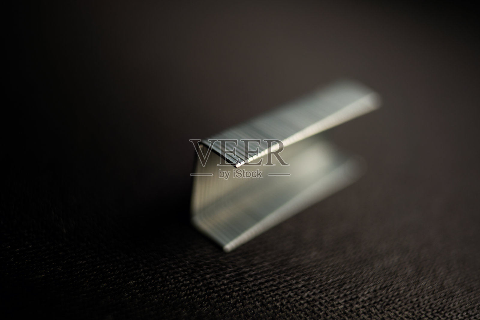 银色金属订书钉特写，放置在深色纹理表面上照片摄影图片