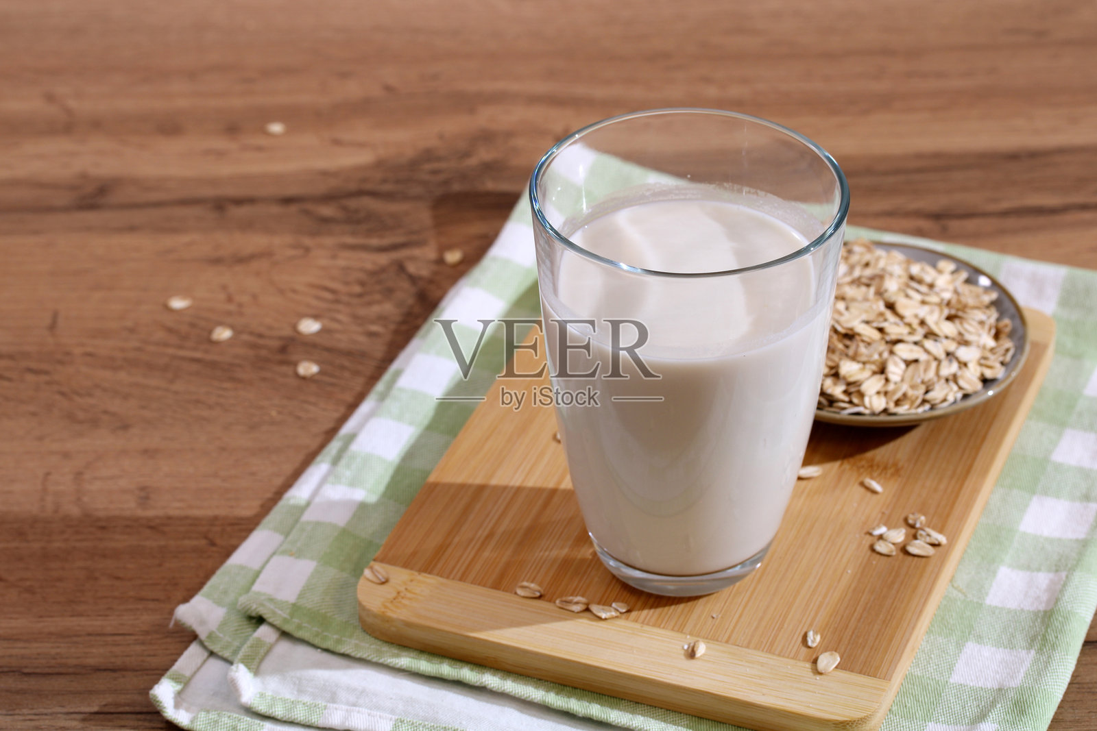 木桌上的燕麦牛奶杯，旁边有燕麦照片摄影图片