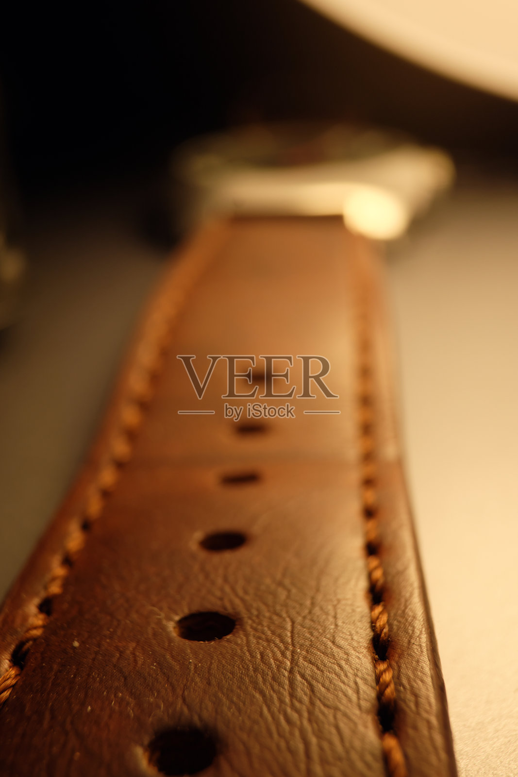 低角度微距拍摄的带孔细节的棕色皮革表带照片摄影图片