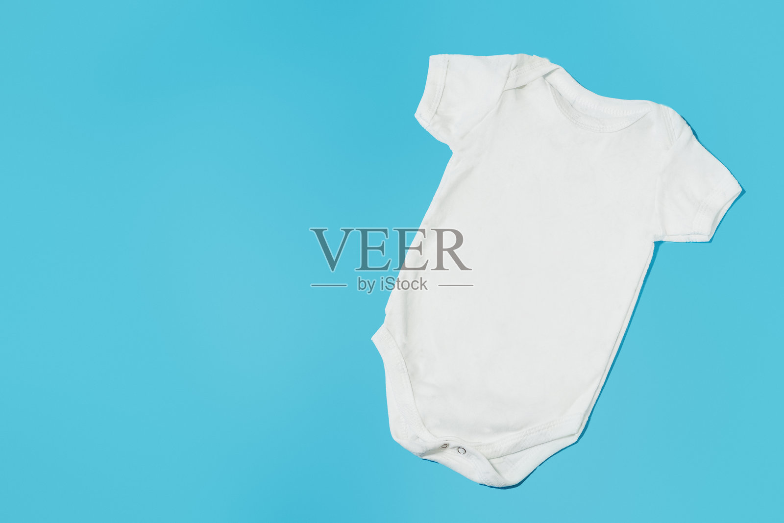 白色婴儿连体衣，孤立在蓝色背景上照片摄影图片