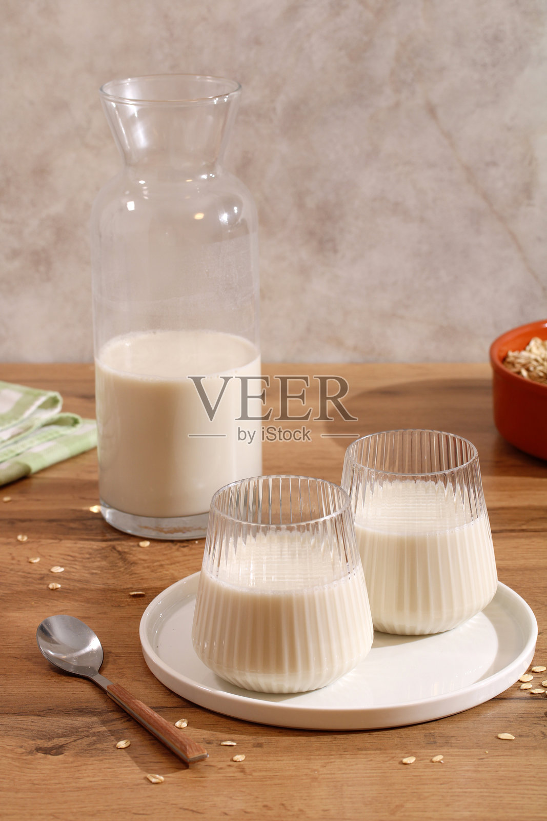 桌上的玻璃壶和燕麦奶杯。植物基替代奶照片摄影图片