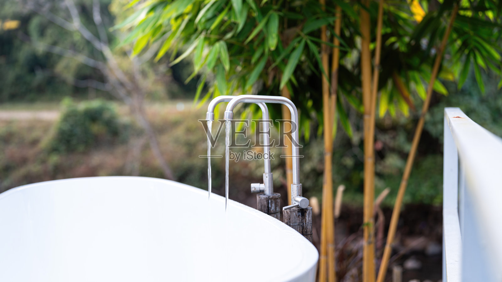 在美丽的花园环境中往浴缸里注水。照片摄影图片