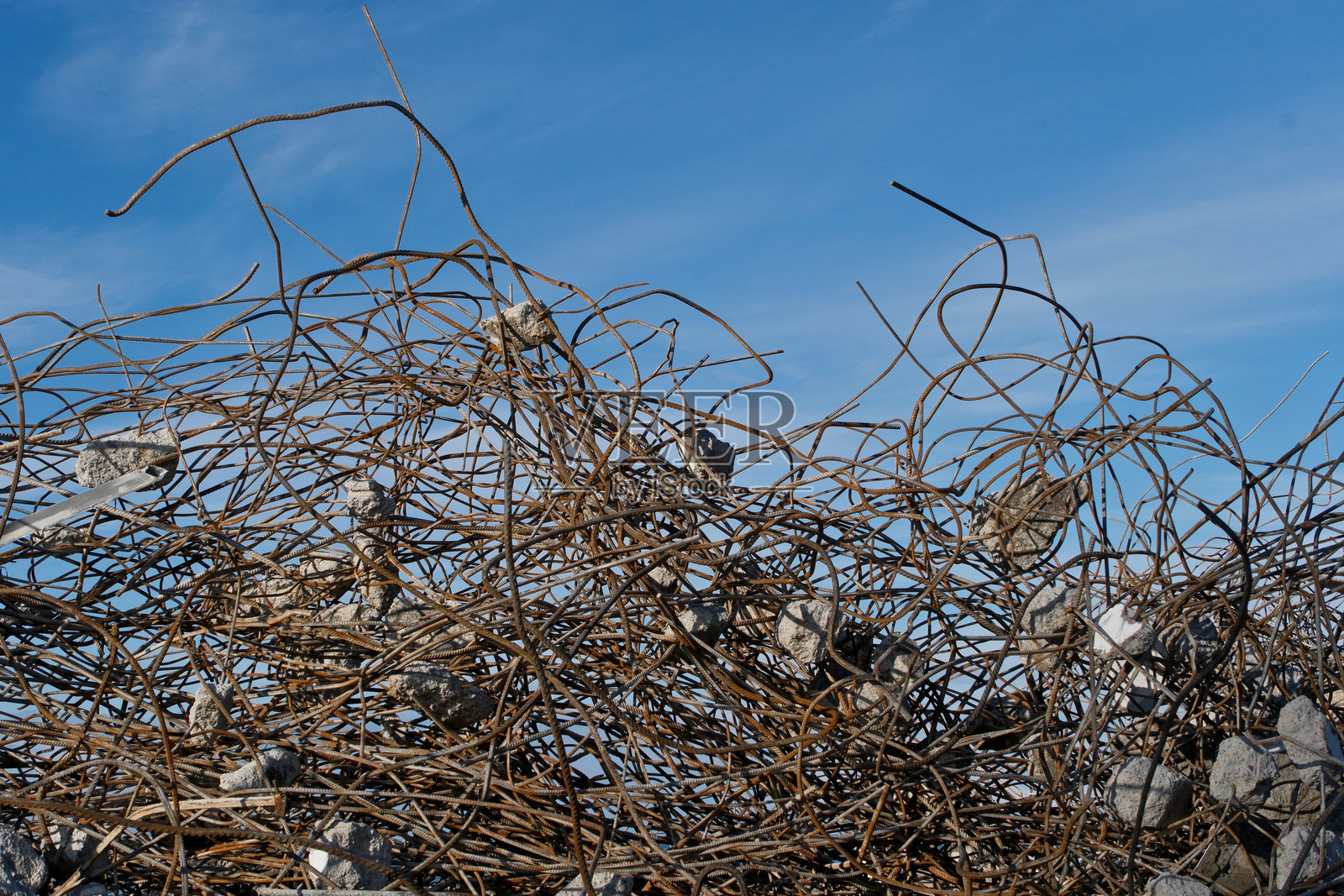 蓝天白云背景下的钢筋混凝土墙遗址，建筑工地上生锈的钢筋和混凝土碎片。照片摄影图片