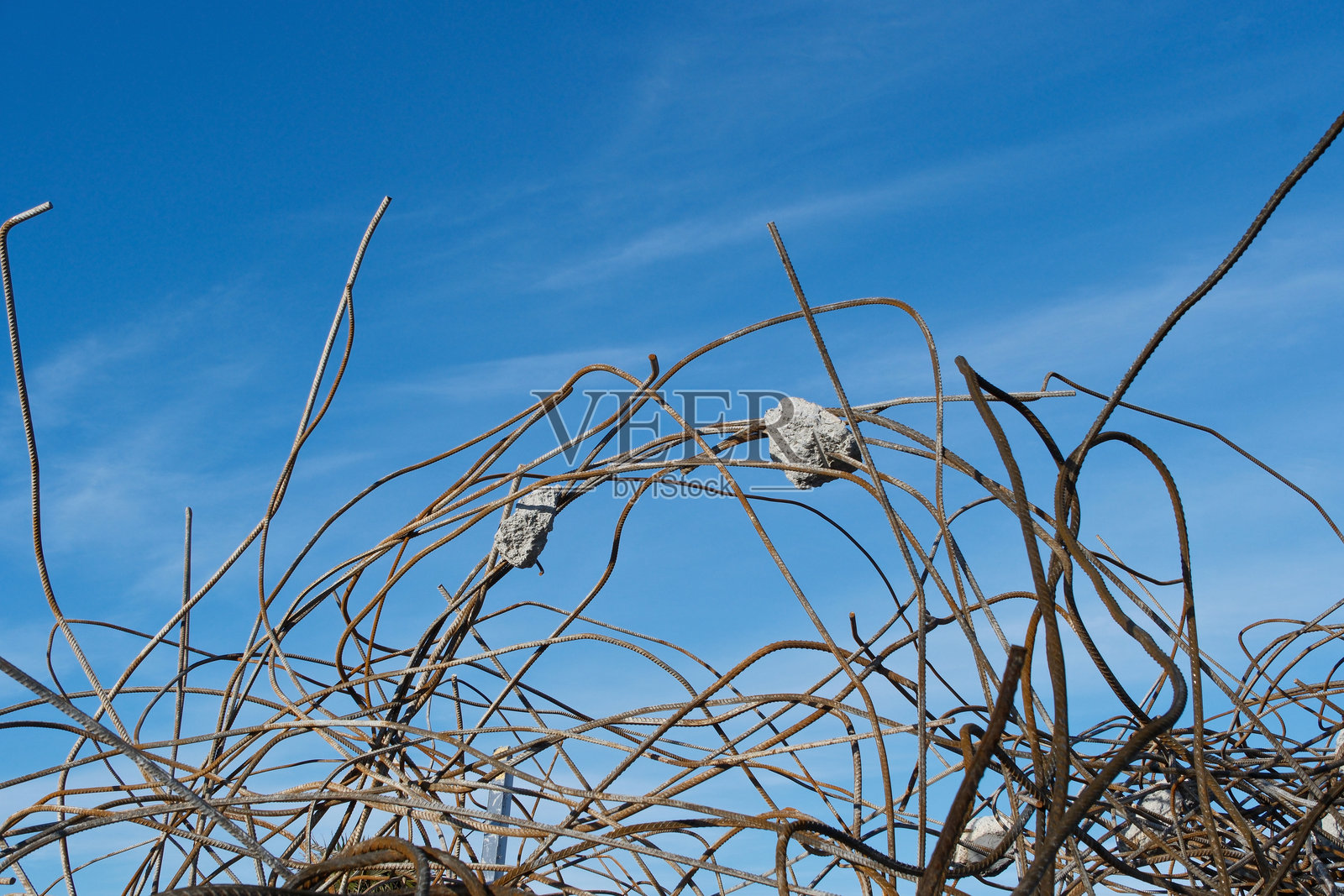 蓝天白云背景下的钢筋混凝土墙遗址。建筑工地上有生锈的钢筋和混凝土碎片。照片摄影图片