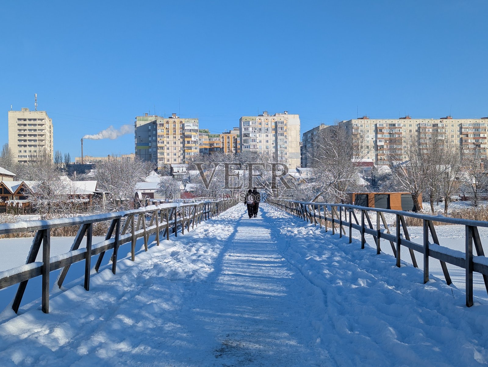 晴朗的阳光下，美丽的冬季风景，有结冰的池塘和被雪覆盖的木桥照片摄影图片