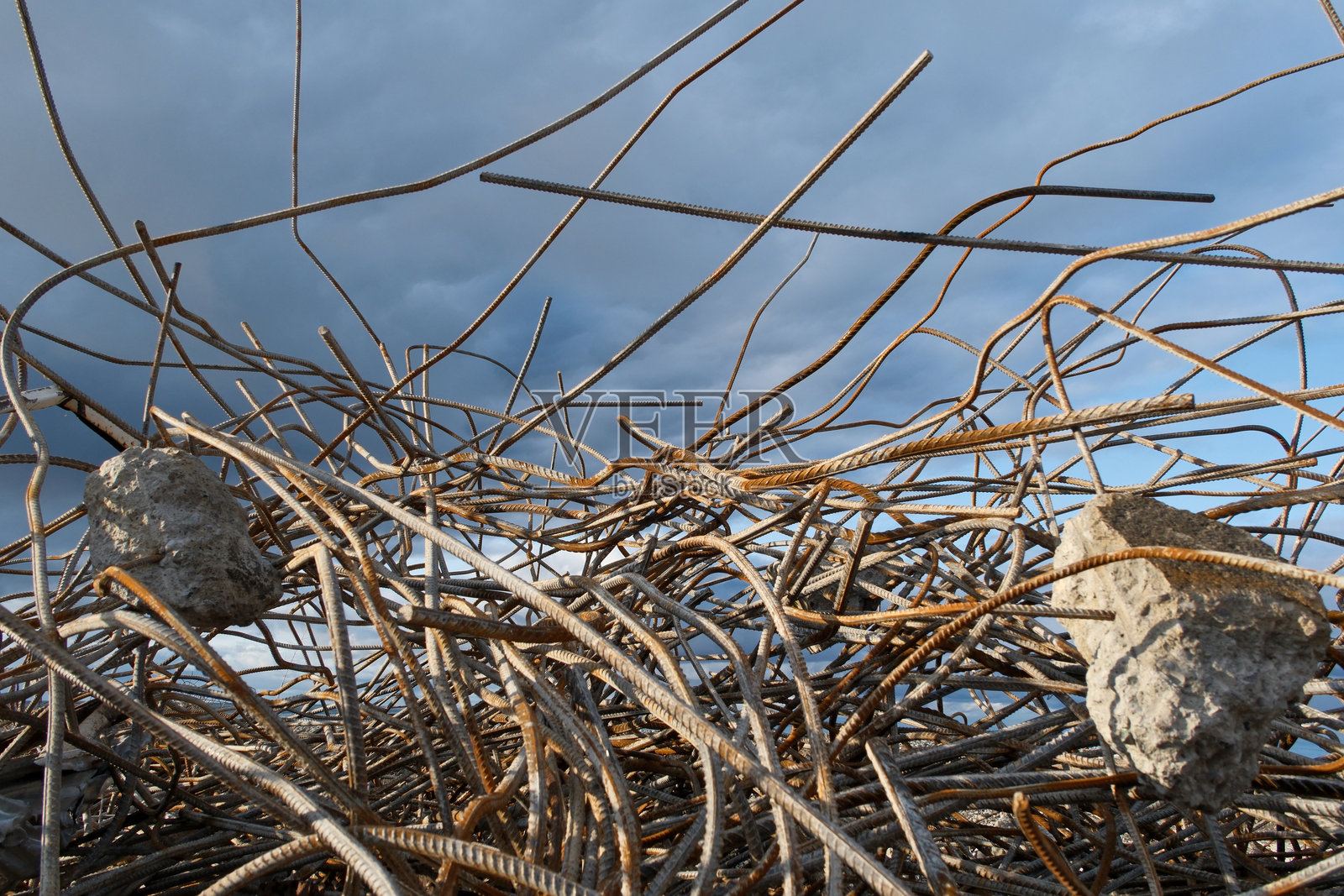 蓝天白云背景下的钢筋混凝土墙遗址，建筑工地上有生锈的钢筋和混凝土碎片。照片摄影图片
