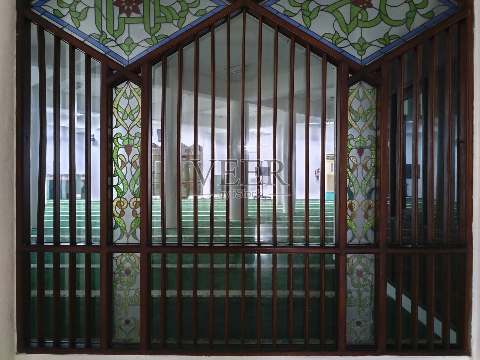 清真寺内部，铺设着绿色祈祷毯，窗户装饰华丽照片摄影图片