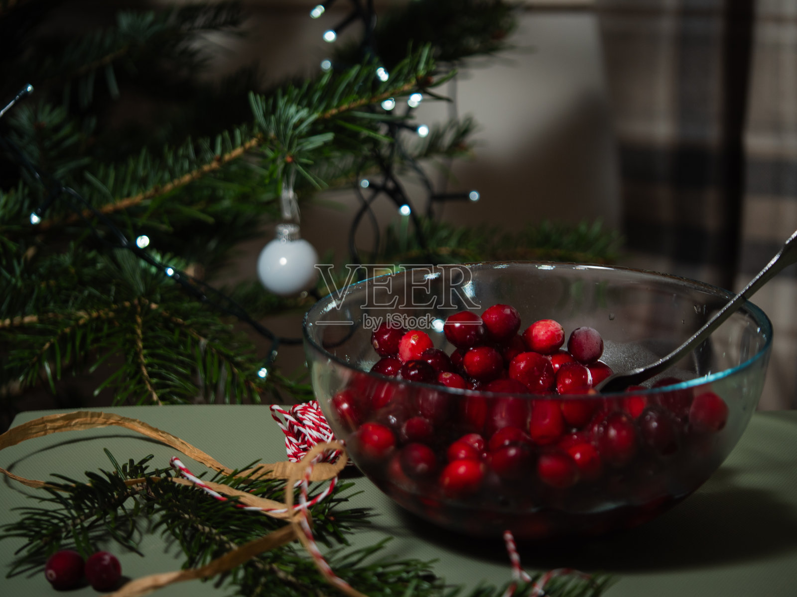 碗里的鲜红成熟蔓越莓，背景是圣诞树灯光照片摄影图片