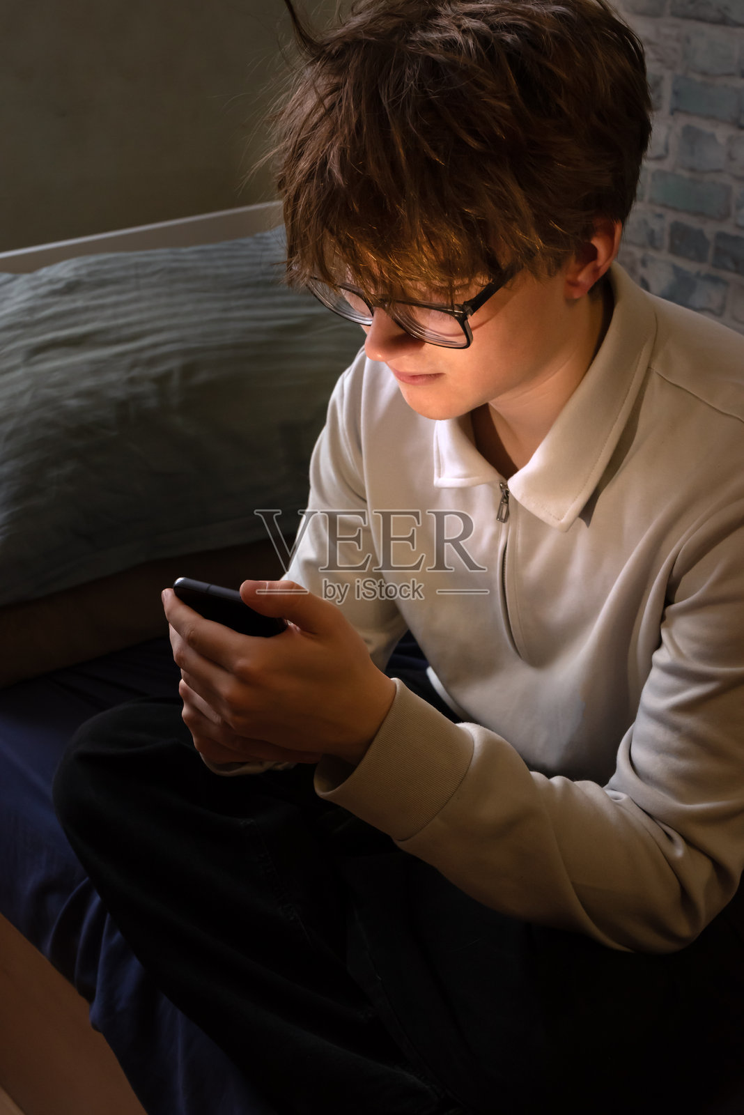 不开心、有压力的年轻男孩坐在那里玩手机照片摄影图片