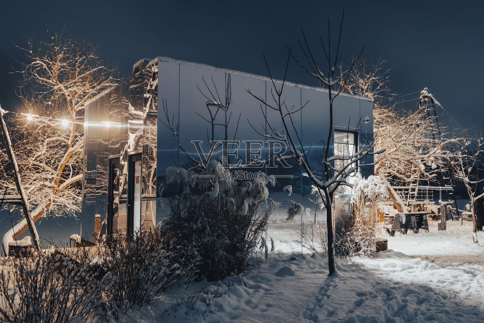 夜晚，现代镜面咖啡馆灯火辉煌。迷人的冬日氛围，倒映着城市灯光。照片摄影图片