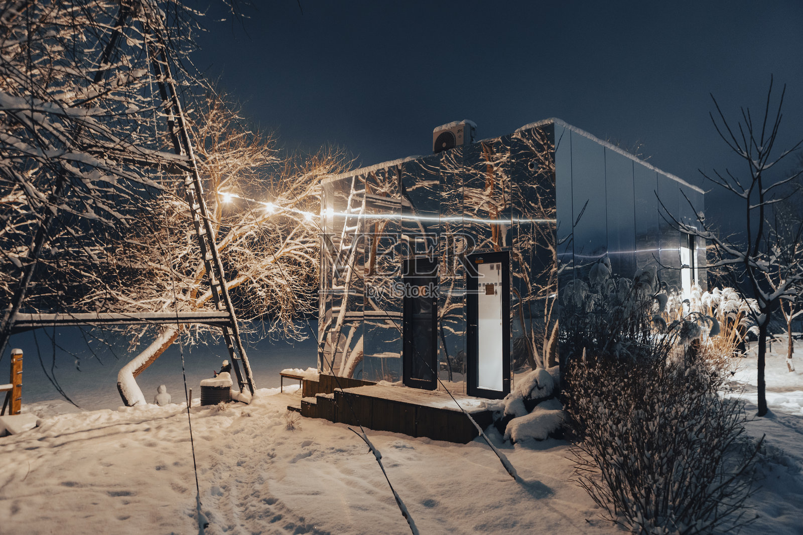 冬季时尚的镜面店面。黄昏时分，温暖的咖啡馆灯光映照在冰面上。照片摄影图片