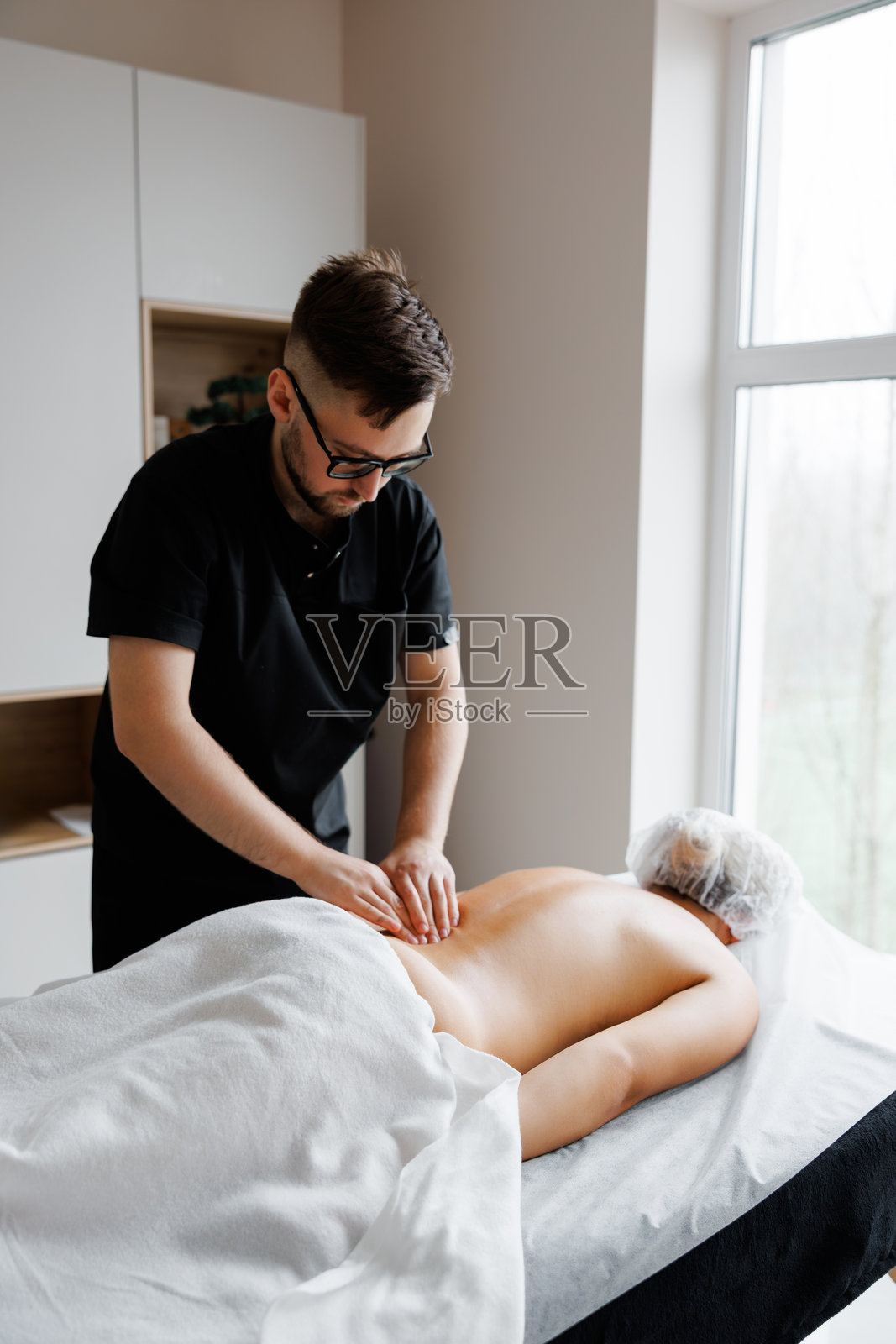 男治疗师在健康理疗中为女性按摩背部照片摄影图片